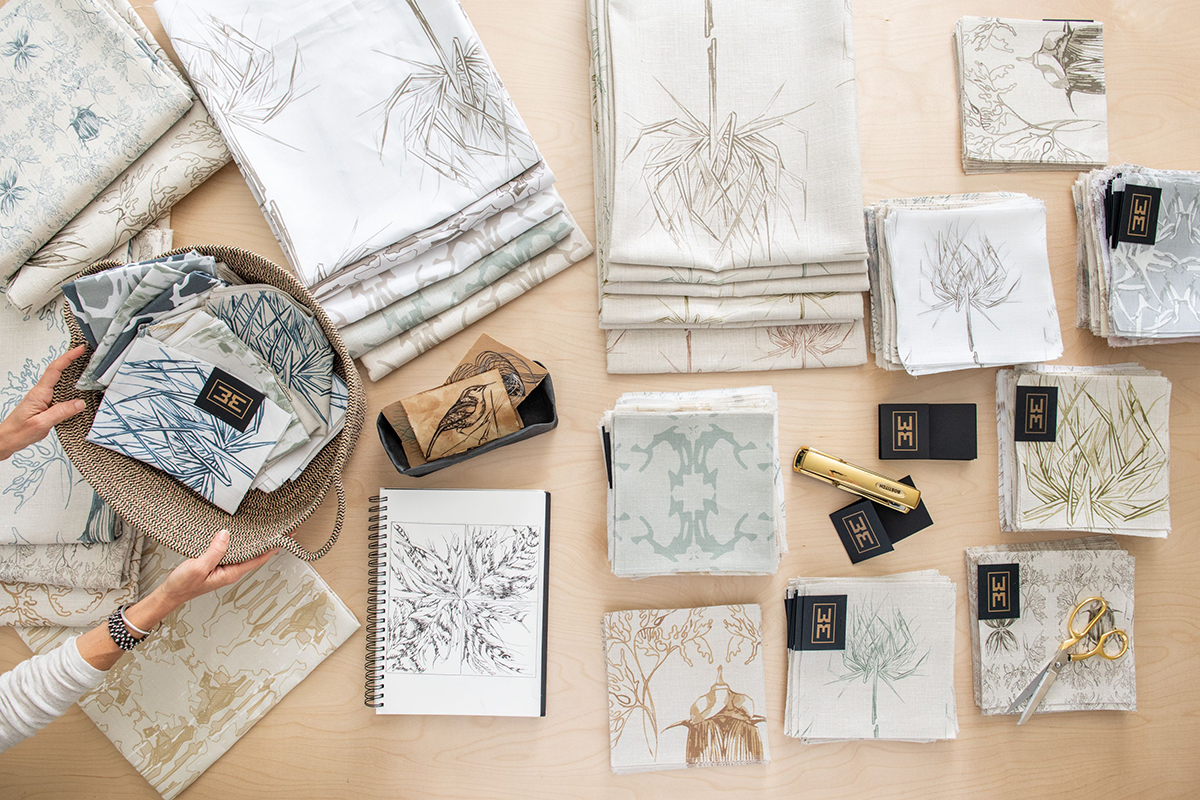Collection of patterned fabric swatches and design sketches on a table.